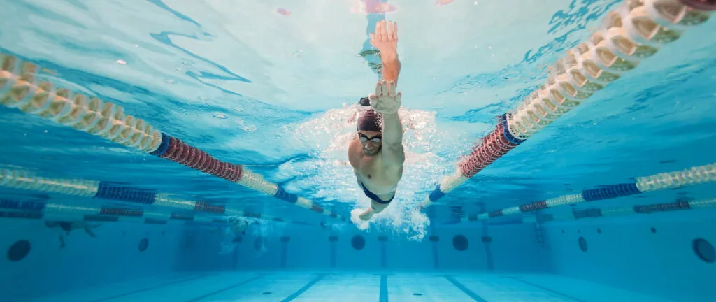 Swimmer performing butterfly stroke underwater in a lap pool with lane dividers